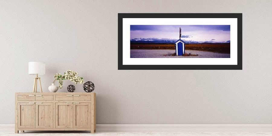 Framed photo artwork of Irishman Creek hut by Richard Hume on wall with cabinet, Tekapo, New Zealand