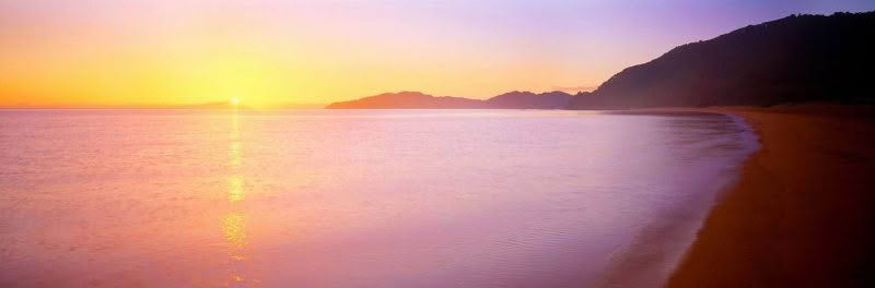 Sunrise Totaranui Beach, Abel Tasman National Park, New Zealand. The sun is rising over Totaranui Beach creating a stunning glow of light