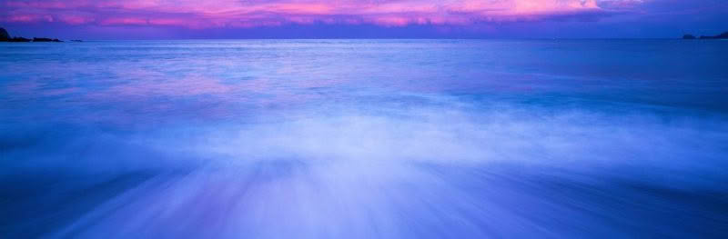 Wave in motion, beach in bay of islands with crashing wave and dramatic dawn light