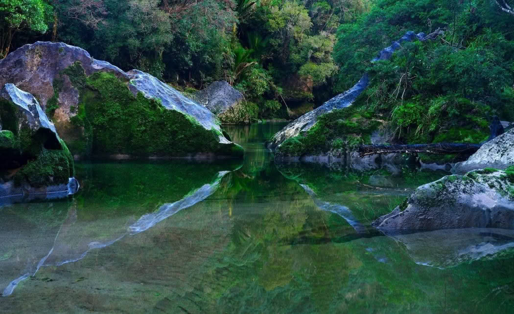 New Zealand Landscape Photography Pororari Stillness. Limestone boulders reflected in Poroari River on the West Coast of the South Island