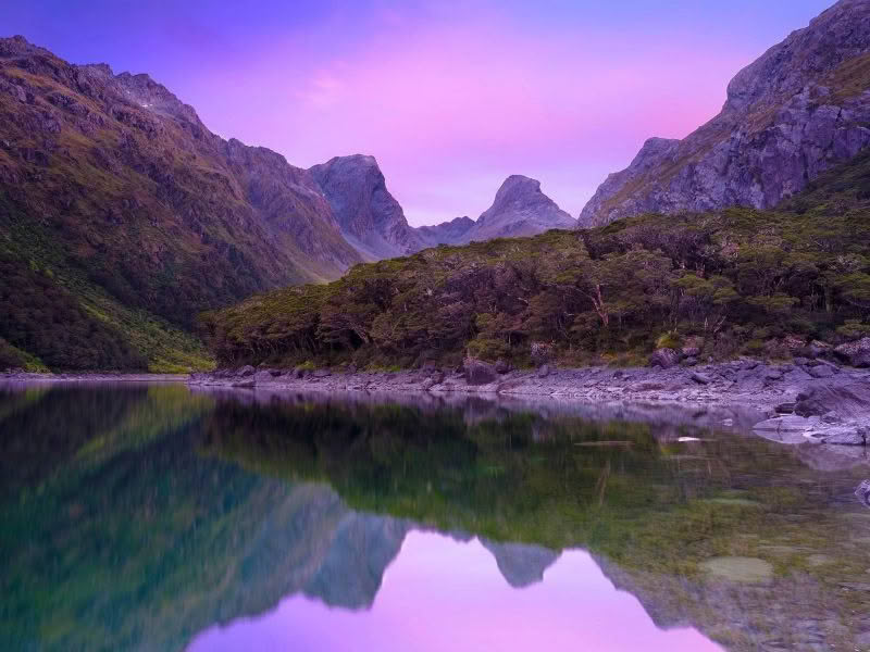 Lake Mackenzie on the Routeburn Track in Fiordland New Zealand. Landscape scene with mountains reflecting in lake at dawn.