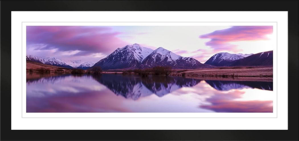 Landscape photography of New Zealand. Lake in Canterbury at dawn with pink sky and reflection of snow capped mountains