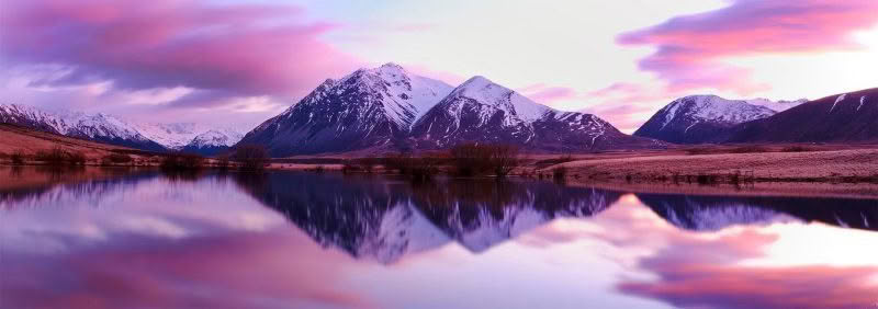 Morning Calm. Lake in Canterbury at dawn with pink sky and reflection of snow capped mountains
