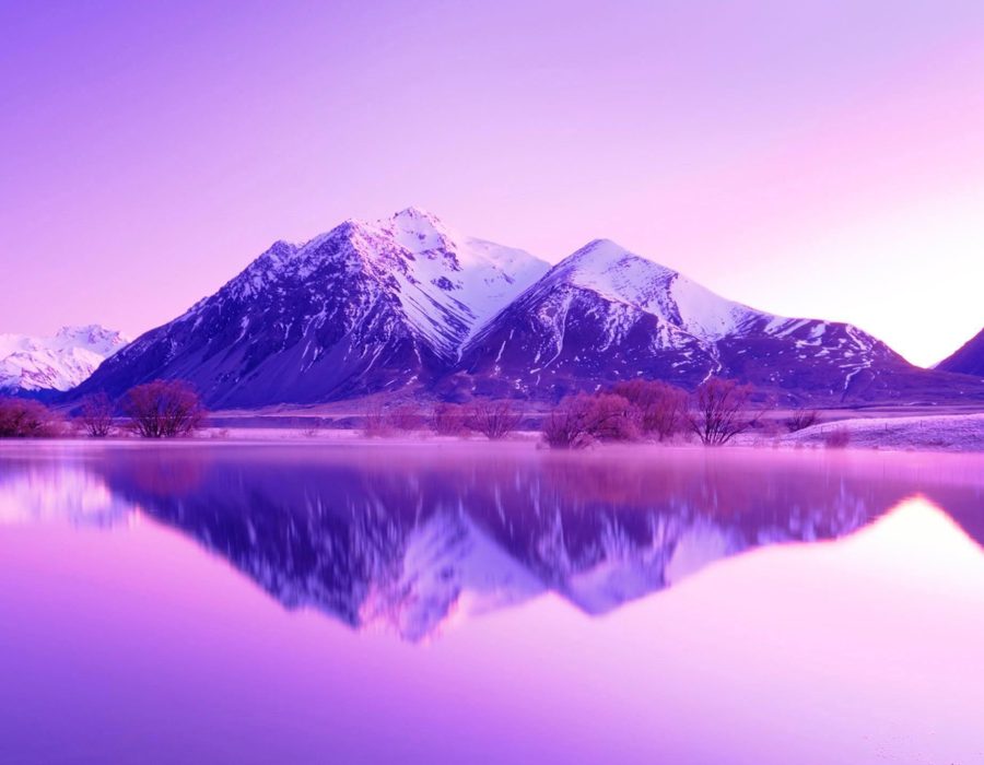 Mountain in Southern Alps with snow and pink dawn light reflected in lake