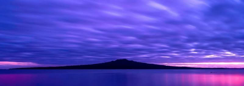 Rangitoto Island at dawn with textured clouds and sunrise light throughout photograph