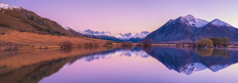 Small lake in Canterbury reflecting snow-capped Southern Alps at dawn