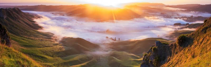 Sunrise over Te Mata Peak, Hawke’s Bay, with fog rolling through the valleys below and warm golden light illuminating the landscape.