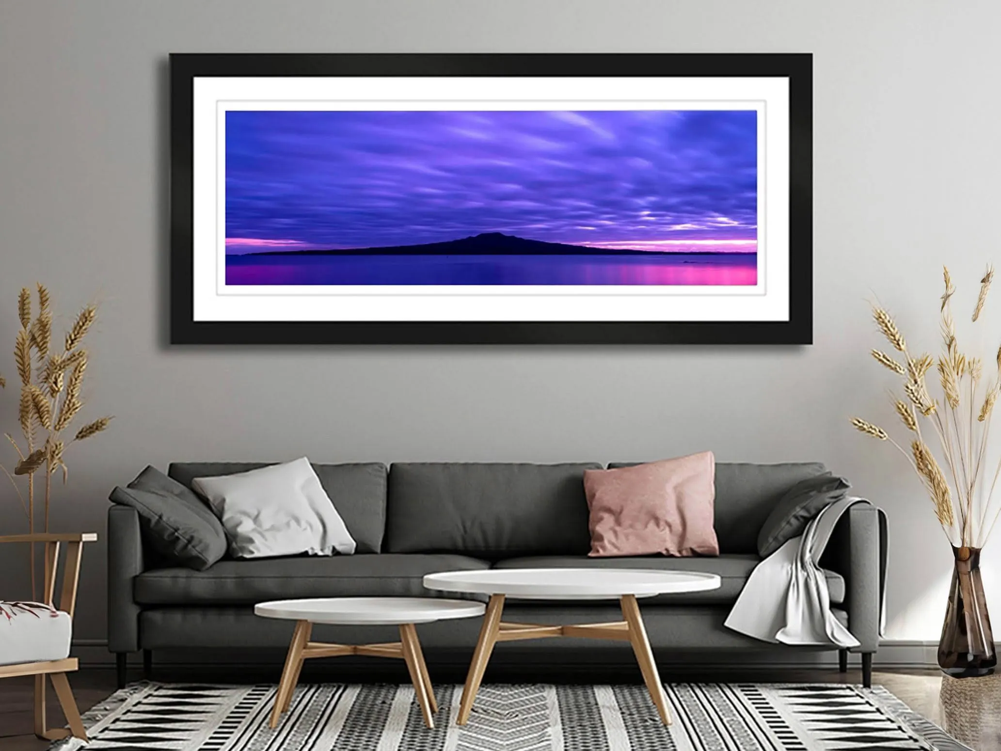 Framed fine art photograph of Rangitoto Island at dawn displayed in a living room interior