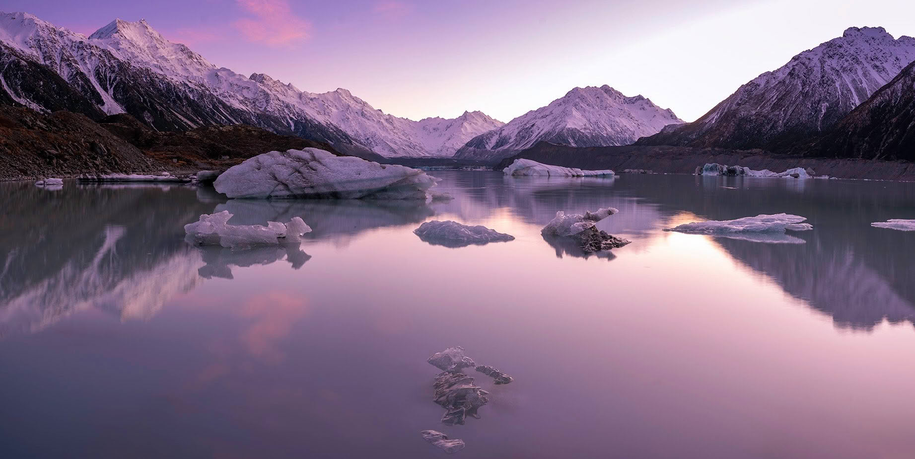 Icebergs and mountain reflections on Tasman Lake at dawn