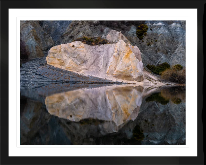 Blue Lake Reflections fine art print in a black frame, showing pale shoreline formations reflected in still water.