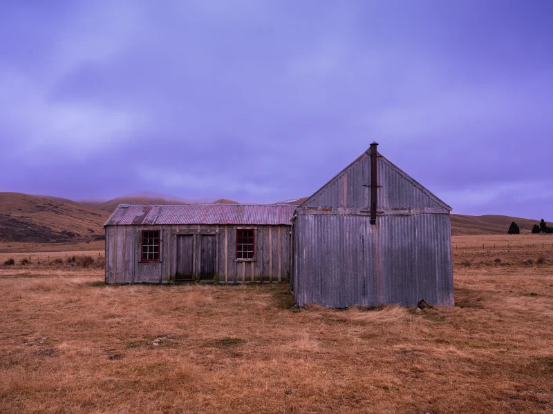 Maniototo Dawn, old rural homestead beneath a soft dawn sky in Central Otago, New Zealand.