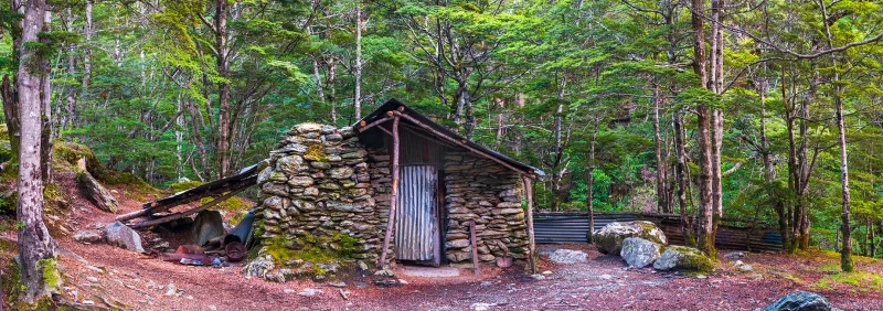 Sam Summers Hut, a historic stone gold miners' hut surrounded by native beech forest near Queenstown, Otago, New Zealand.